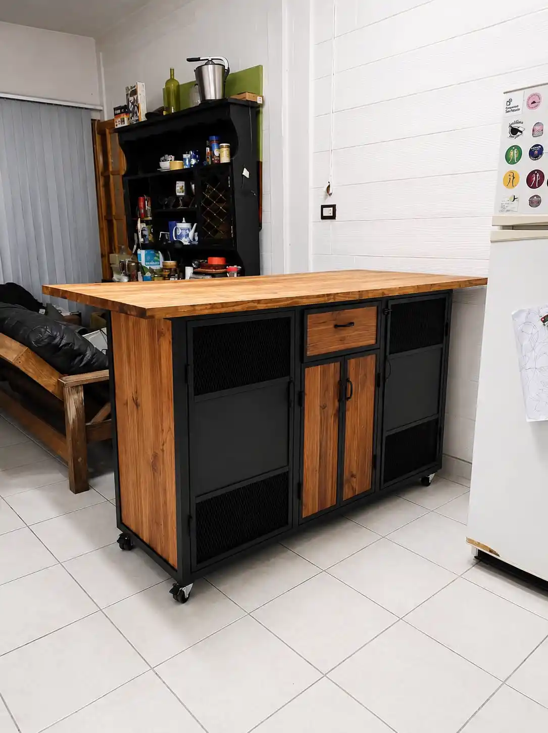 Isla de cocina industrial sobre ruedas con tapa de madera, puertas de malla y estructura de hierro negro